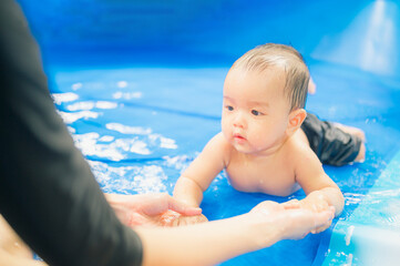Asian mother swimming with cute adorable baby in swimming pool, during  quarantine,Fun holiday concept.