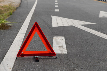 Emergency red warning triangle on the road sign with white traffic line