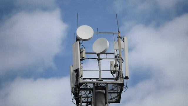 Telecommunication tower with repeaters against a cloudy sky, close-up
