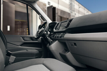 Modern cargo van interior near warehouse. Minivan interior with fabric seats, panel and gearbox...