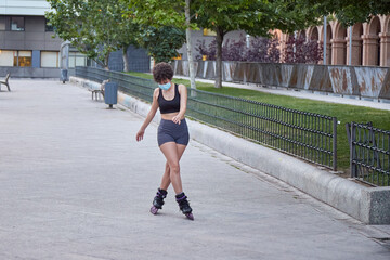 Latin girl skating on inline skates protecting herself with a face mask