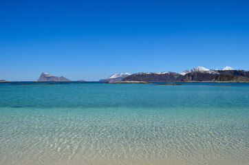 Fototapeta premium majestic white springtime beach with snowy mountain islands in sea on the summer island in northern norway