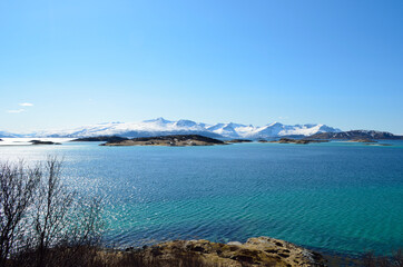 small settlement on sea islands with snowy mountains and sunshine