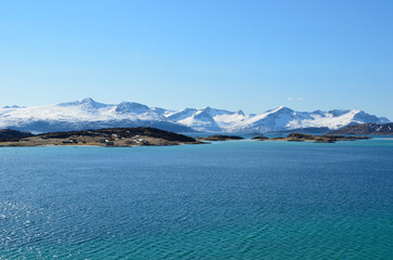 small settlement on sea islands with snowy mountains and sunshine