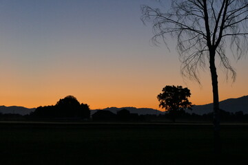Pleasant atmosphere with dawn over rural area and silhouette of settlement and range of hills