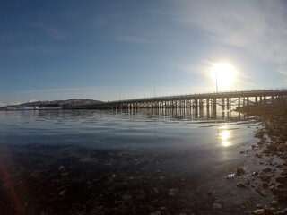 old car bridge over blue fjord as the winter sun is rising