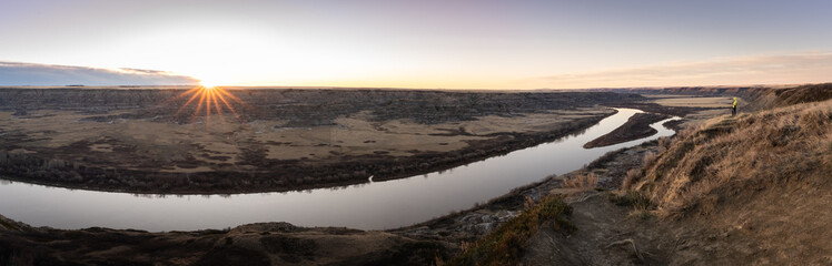Fototapeta premium Panoramic sunrise shot of desert like canyon with river flowing through its bottom, shot in Drumheller region, Alberta, Canada