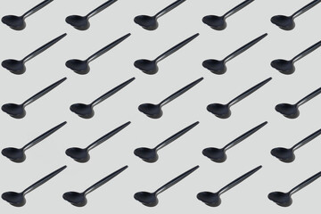 Colourful pattern of black spoons on grey background. View from top.