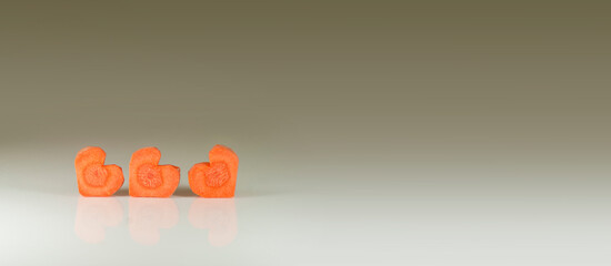 Gray and gold background. Hearts carrots. Valentine's background with hearts. Healthy snacks for a loved one. Baby carrots on neutral background.