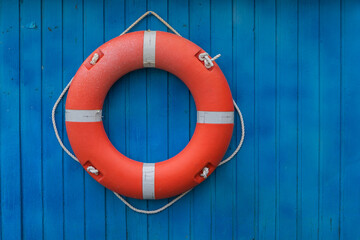 The orange lifebuoy ring hangs on a bright blue wooden wall