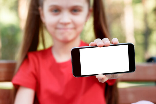 Child Girl in Park Holding a Smartphone With a White Screen