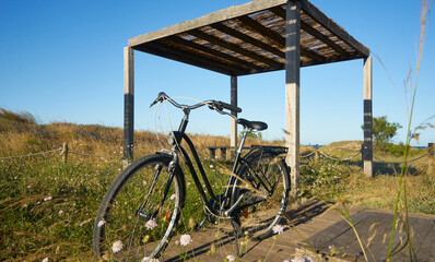Fototapeta na wymiar Bicycle parked next to empty rustic table in front of a landscape with the sea in the background. Nature walk concept