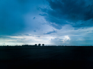 Blue cloudy sunset with silhouettes of trees far away