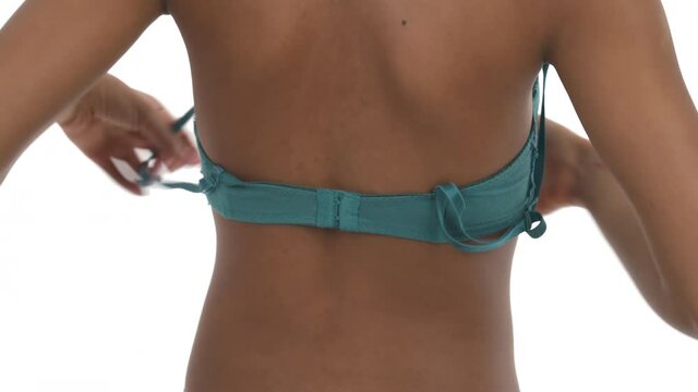 Close-up back view of a woman hooking the clasp of her bra. Isolated, on white background