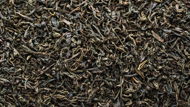 Black large-leaf tea as a background. Texture of dry black tea leaves.