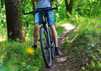 Fototapeta na wymiar A young man rides a Bicycle on country roads close up