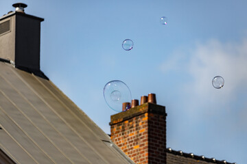 Big soap bubbles in air with  chimney  in the background in Ghent, Belgium