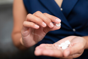 Close up of working woman taking in pill she is pours the pills out of the bottle,taking painkiller to reduce sharp ache concept,health care and medicine concept.