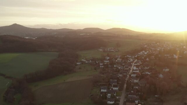Cinematic drone / Aerial fly away shot of a sunset of a little village at a beautiful, vibrant color sunset, Oelberg, Siebengebirge, Bonn, Königswinter 24p