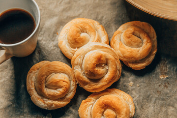 Chelsea buns with cup of coffee. Freshly baked rolls buns on a brown  background
