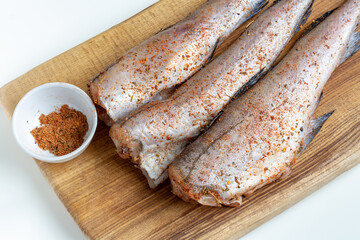 Pollock fish with spices on a wooden board