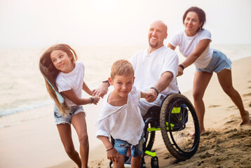 Disabled man in a wheelchair with his family on the beach.