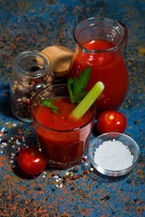 healthy tomato juice with salt and celery on dark background, top view