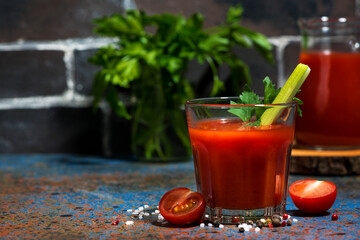 healthy tomato juice with salt and celery on dark table