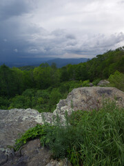 The storm clouds are parting and the sun shines through onto the land below.