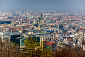 Obraz premium Beautiful morning top view of Budapest. Cathedral of St. Stephen and the Ferris wheel. Roofs of houses. Spring. Selective focus in center.