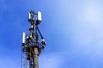 The top of the cell tower against a sunny blue sky