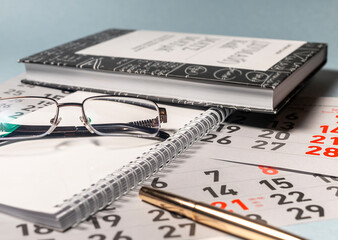 eyeglasses on a white notebook planner with book of maths black and white on calendar sheets. maths...