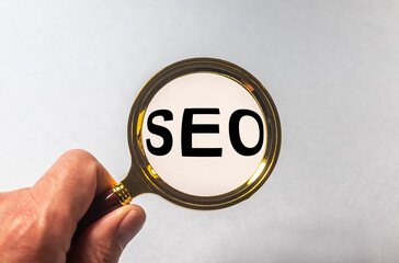 magnifier in hand and inscription SEO, seo search concept isolated on blue background