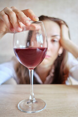 Drunk woman sad looking at a glass of wine.