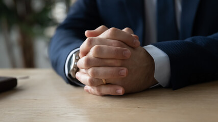Crop close up of clasped clenched Caucasian businessman hands on desk in office, show confidence power, determined male boss or leader thinking pondering making decision or solution at workplace © fizkes