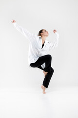 Dancer in jazz poses on the floor of her fingers on a white background. Girl, beautiful, modern, choreography, performance, style, shirt