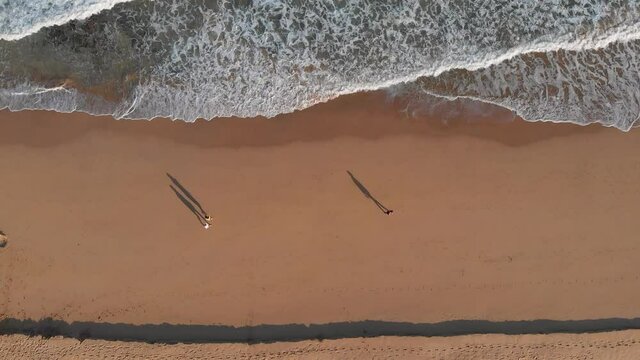 Aerial top down view people walking beach shoreline with shadows, Porto Santo Island 