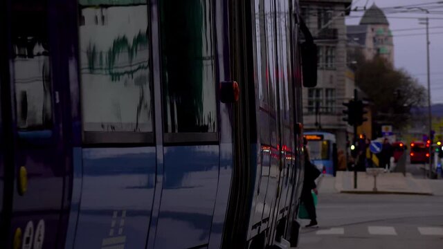 reflections over a tram side that stops in the middle of crowded city at evening