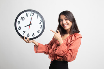 Young Asian woman point to a clock .