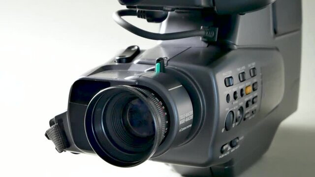 The video camera with the microphone isolated on white, in concept of technology, entertainment. Retro camcorder