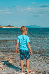 Fototapeta na wymiar little boy on the beach watching the sea