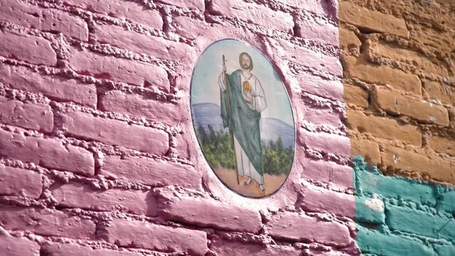 Religious Painting of Jesus on a Pink, Orange, and Green Wall. Footage from San Miguel de Allende, in Mexico. Colorful, shot on a gimbal, and very traditional.