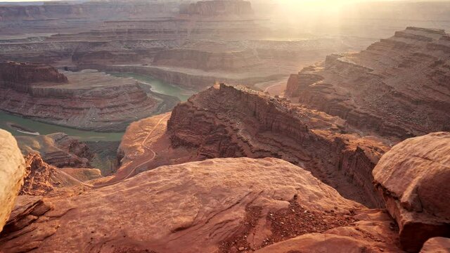 Going to edge of cliff to see view on red rocks and Colorado River during sunset in Dead Horse Point State Park, Utah, USA. Steadicam shot, UHD