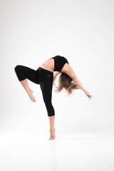 Fototapeta na wymiar Girl dancer in a pose with a backbend on a white background. Gymnastics, dance, preparation, contemporary, practice, workout, strength, flexibility, stretching, performance.