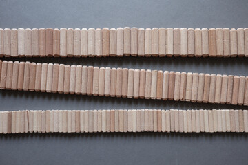 Holzdübel in verschiedenen Größen auf grauen Hintergrund bilden ein umgedrehtes Z