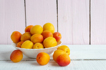 Fresh apricots on a plate on a wooden background. Summer harvest