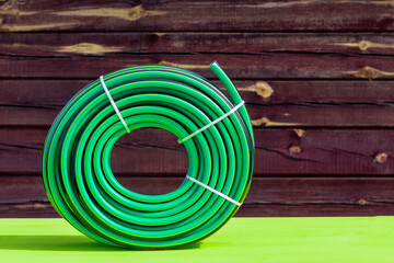 daylight. bright sun. On a yellow wooden background in retro style. Rubber watering hose twisted in...