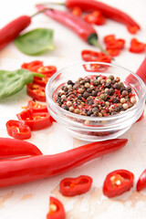 Hot chili pepper and bowl with peppercorn on light background