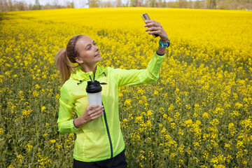 A girl in a bright sports jacket takes a selfie after training against the background of a blooming...