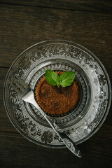 Chocolate brownie on a serving plate decorated with mint leaf on top.